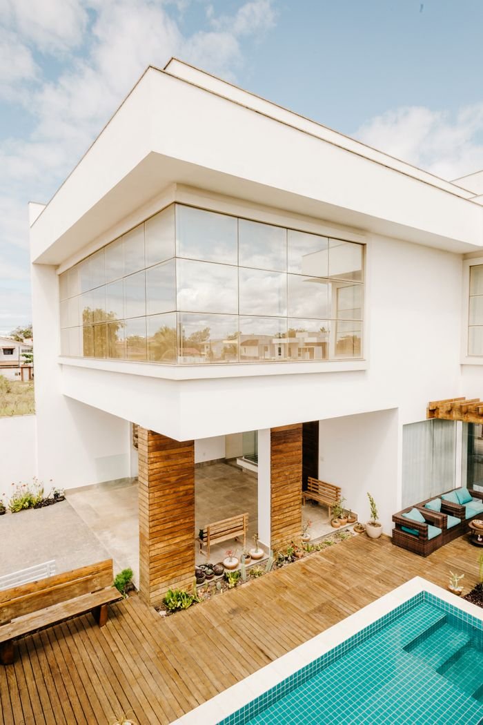 Elegant luxury home exterior featuring glass facade, wooden accents, and a swimming pool in a modern setting.